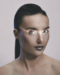 Frau mit Lichtreflexion im Gesicht vor grauem Hintergrund - MOMF00973
