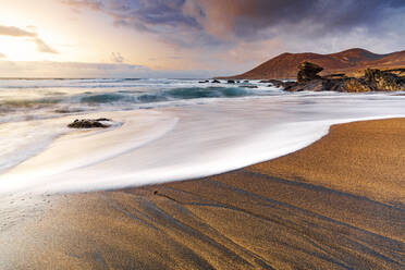 Schaum von Meereswellen auf goldenem Sandstrand bei Sonnenuntergang, Playa de la Solapa, Pajara, Fuerteventura, Kanarische Inseln, Spanien, Atlantik, Europa - RHPLF20956