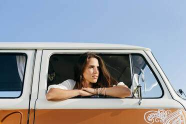 Schönes brünettes Mädchen in einem Van lehnt sich an das Fenster und schaut in die Sonne - ADSF32204