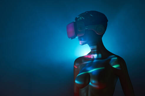 Dummy einer Frau mit futuristischer VR-Brille unter heller Projektion im abgedunkelten Raum - ADSF32301