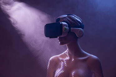 Female dummy with VR goggles placed against bright purple background as symbol of futuristic technology - ADSF32305