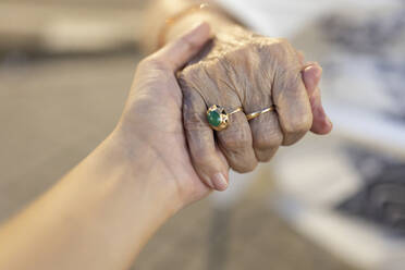 Granddaughter and grandmother holding hands of each other - EGHF00271