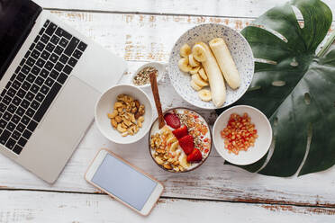 Mobile phone and laptop by healthy brunch on table - EGHF00280