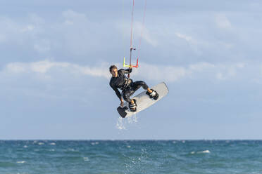 Mann beim Kiteboarden über Wasser im Urlaub - DLTSF02452