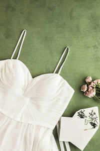 Studio Schuss von weißen Hochzeitskleid, Einladungskarte und Rosen flach gegen grünen Hintergrund gelegt - FLMF00720