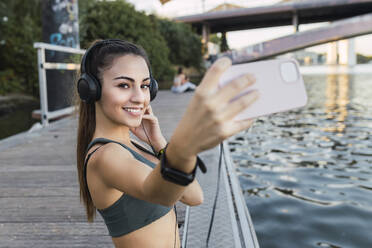 Sportlerin nimmt Selfie durch Handy auf Pier - JRVF02169