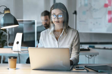 Businesswoman working on laptop in office - JSRF01735