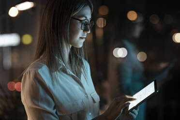 Geschäftsfrau bei der Arbeit am digitalen Tablet im Büro am späten Abend - JSRF01746