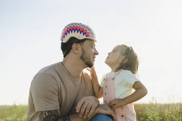 Girl looking at father wearing helmet - SEAF00192