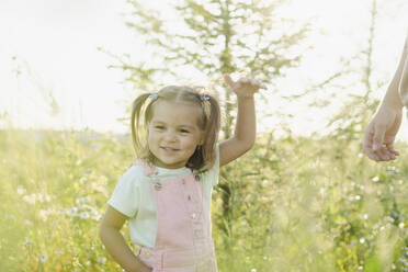 Smiling girl gesturing in front of plants on sunny day - SEAF00198