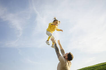 Father throwing daughter in air on sunny day - SEAF00212