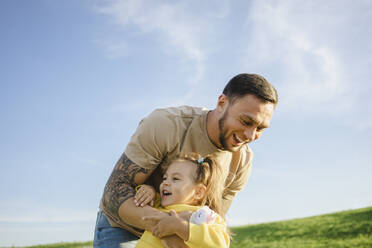 Happy father tickling daughter on sunny day - SEAF00213