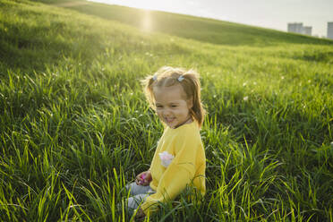 Lächelndes Mädchen spielt im Gras an einem sonnigen Tag - SEAF00221