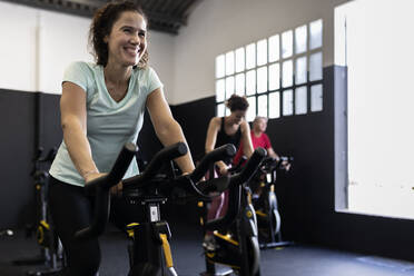 Athletes exercising on bikes in gym - JPTF00942