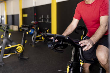 Athlete exercising on bike in gym - JPTF00944