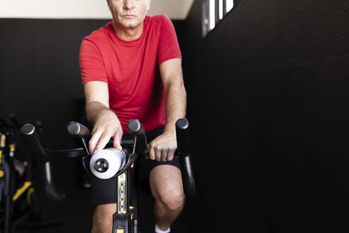 Sportler hält Flasche auf Heimtrainer im Fitnessstudio - JPTF00949