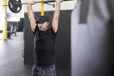 Sportler mit erhobenen Armen beim Kreuzheben im Fitnessstudio - JPTF00964