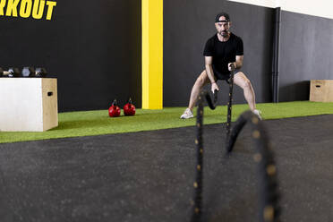 Sportler beim Üben mit Kampfseilen in der Turnhalle - JPTF00967