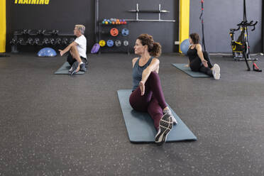 Sportler üben Dehnungsübungen auf Yogamatten im Fitnessstudio - JPTF00977