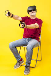 Man playing virtual video games on chair - GPF00260