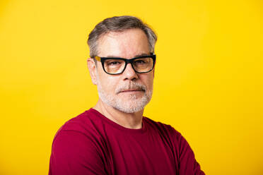 Man wearing eyeglasses against yellow background - GPF00265