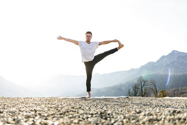 Mann übt Utthita Hasta Padangusthasana mit Blick auf die Berge - OMIF00199