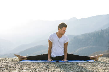 Mann übt Samakonasana mit Blick auf die Berge - OMIF00206