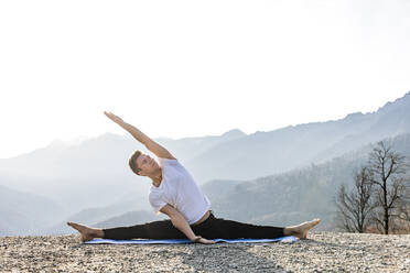 Mann übt Yoga mit Blick auf die Berge - OMIF00208