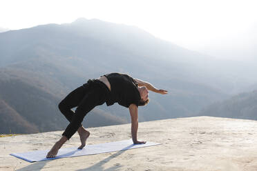 Mann übt Camatkarasana an einem sonnigen Tag - OMIF00212