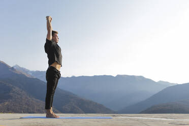 Man practicing Urdhva Hastasana with mountain view - OMIF00213