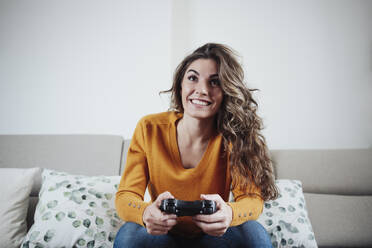 Junge Frau spielt ein Videospiel zu Hause - EBBF04933