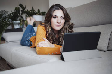 Frau mit Tablet-PC auf dem Sofa zu Hause liegend - EBBF04948