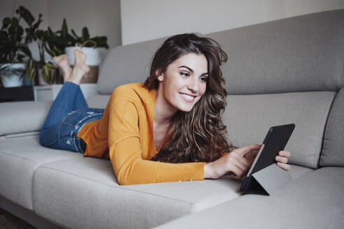 Lächelnde Frau, die zu Hause einen Tablet-PC benutzt - EBBF04950