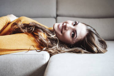 Lächelnde Frau auf dem Sofa zu Hause liegend - EBBF04964