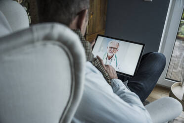 Doctor advising patient on video call through tablet PC at home - UUF25238