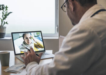 Patient mit Kopfschmerzen im Gespräch mit einem Arzt per Videoanruf in der Klinik - UUF25244