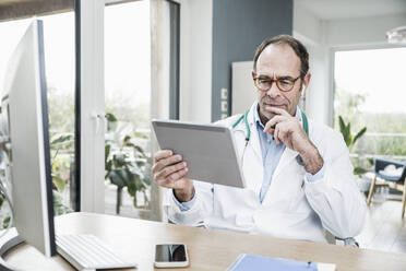 Arzt schaut auf Tablet-PC im Krankenhaus - UUF25256
