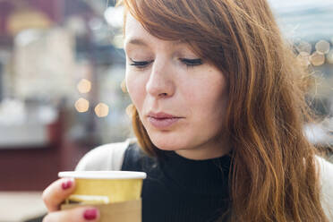 Woman blowing coffee in disposable cup at cafe - WPEF05567