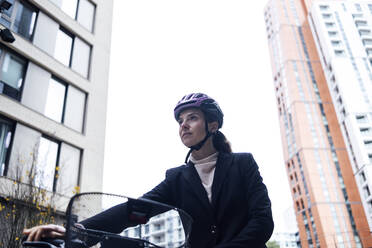 Geschäftsfrau mit Helm beim Radfahren in der Stadt - ASGF01843