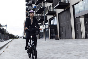 Geschäftsfrau fährt Elektrofahrrad auf der Straße in der Stadt - ASGF01844