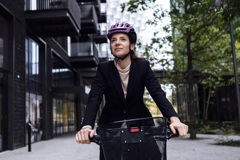 Businesswoman riding electric bicycle in city - ASGF01845