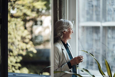 Ältere Geschäftsfrau mit Kaffeetasse und Blick aus dem Bürofenster - JOSEF05993