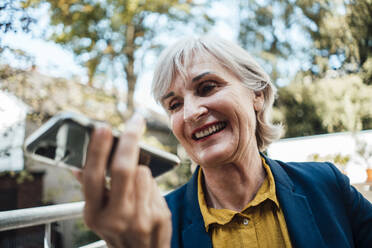 Ältere Geschäftsfrau sendet Sprachnachricht über Smartphone auf Terrasse - JOSEF06015