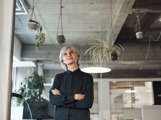 Thoughtful businesswoman with arms crossed in office - JOSEF06036