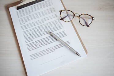 Agreement contract with pen and eyeglasses at office desk - EBBF04979