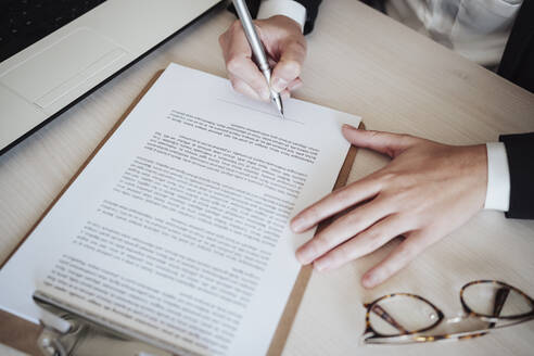 Businesswoman signing documents with pen at office - EBBF04981