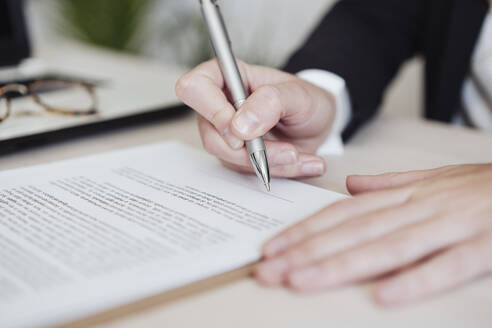 Immobilienmakler beim Unterzeichnen eines Dokuments im Büro - EBBF04997