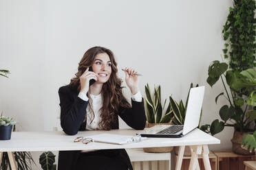 Smiling businesswoman talking on smart phone at office - EBBF05012