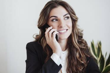 Nachdenkliche Geschäftsfrau, die mit einem Smartphone telefoniert - EBBF05020