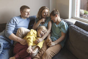 Man looking at family laughing on sofa - IHF00694